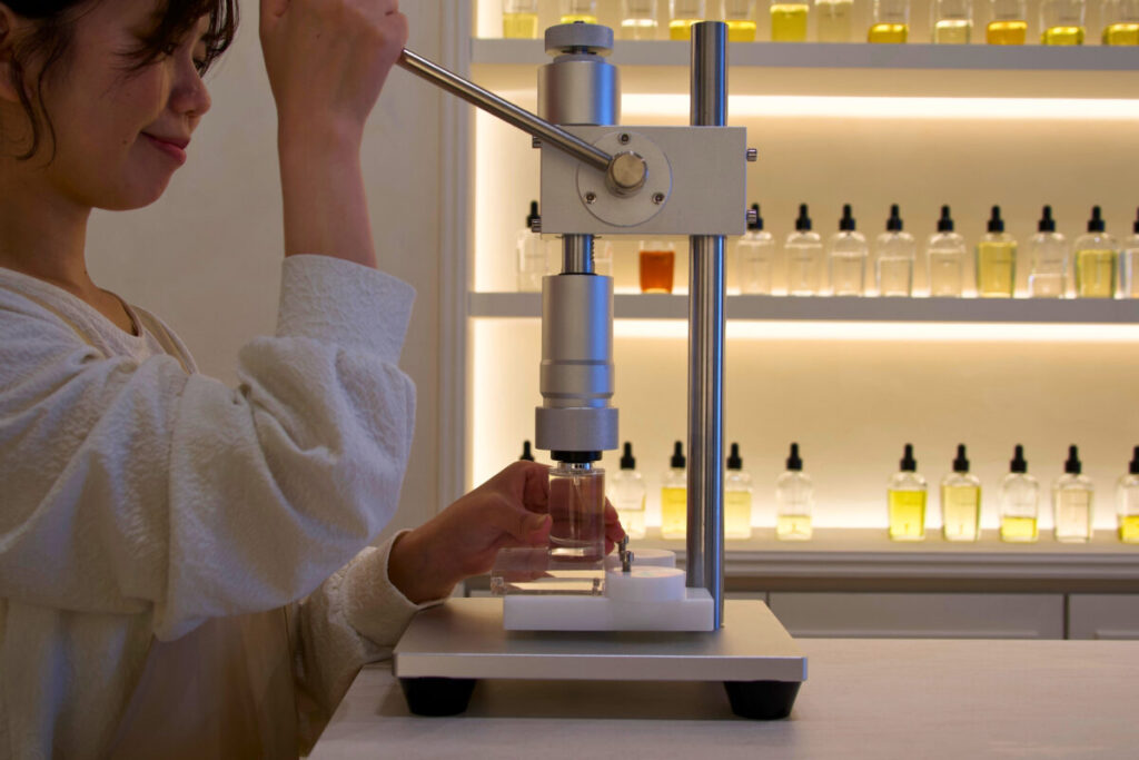 CABINET_ボトルを器具で密封する工程を体験する様子
