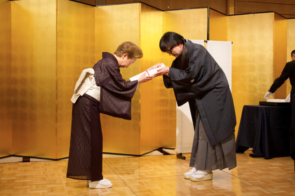 京都五花街の芸妓組合長へ紗綾形の白生地を手渡す永楽屋の反物寄贈式