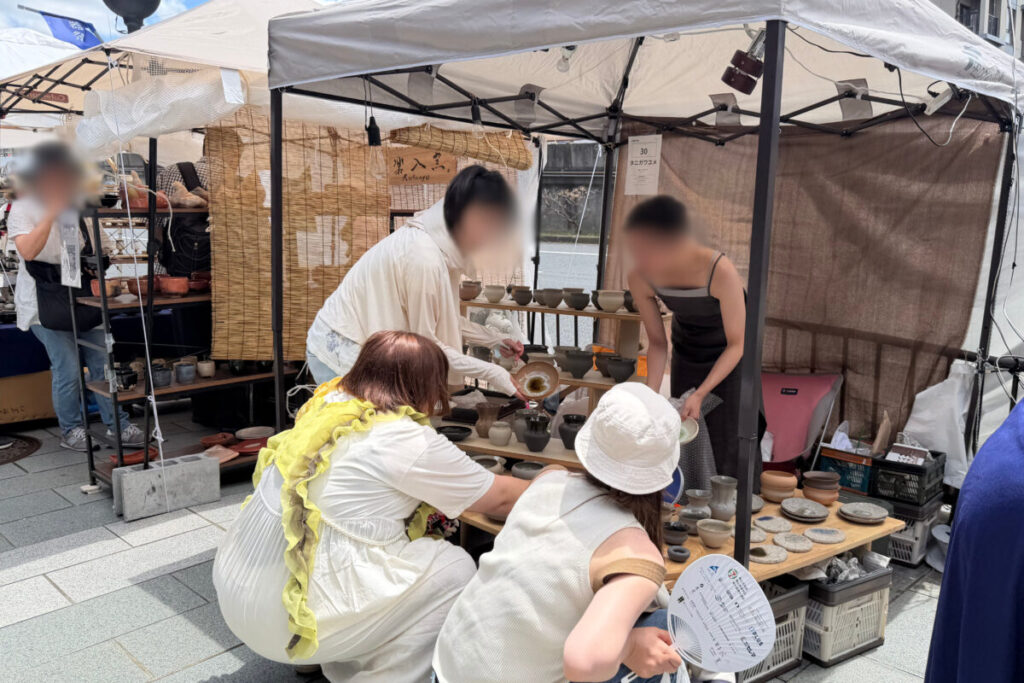 五条若宮陶器祭のテントで作家と話しながら器を選ぶ来場者