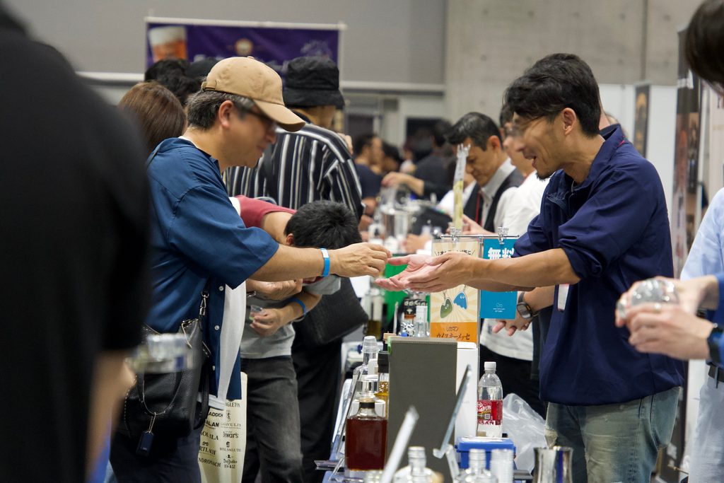 ウイスキーメッセのブースで説明を聞きながら試飲する来場者