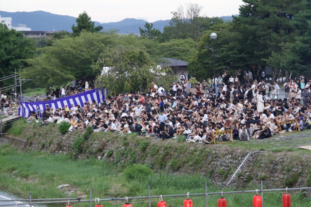 嵐山灯籠流しを待つ桂川沿いの人々
