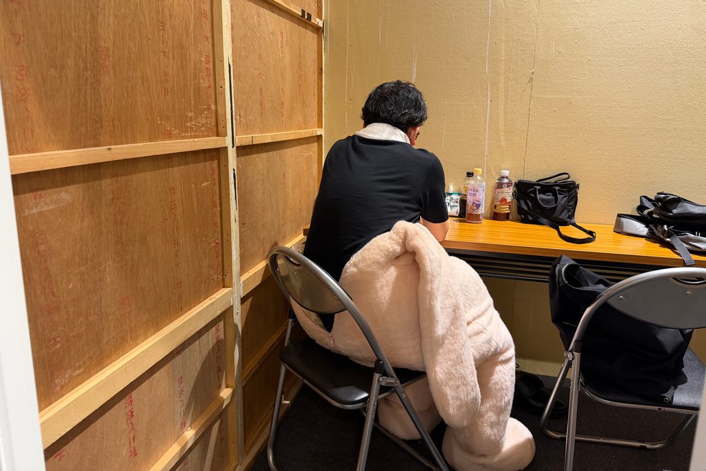 着ぐるみの上半身を脱いで休憩する人の展示