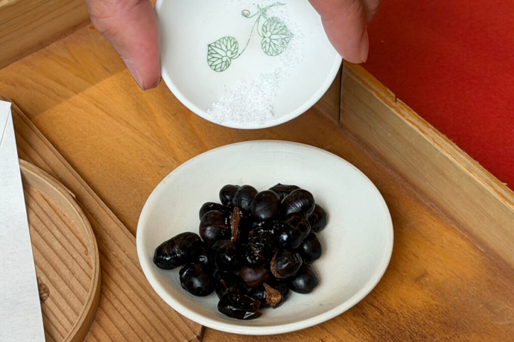 小皿に移した黒豆に塩を振る様子